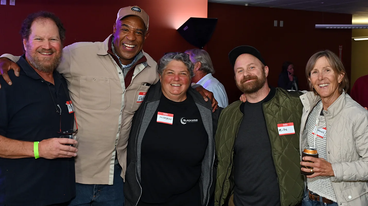 Five smiling attendees with name tags posing arm in arm at the Boulder County Film Commission fall event
