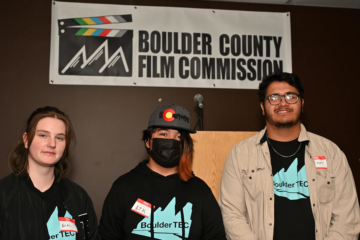 Three BoulderTEC students standing in front of the Boulder County Film Commission banner at the 2022 fall event