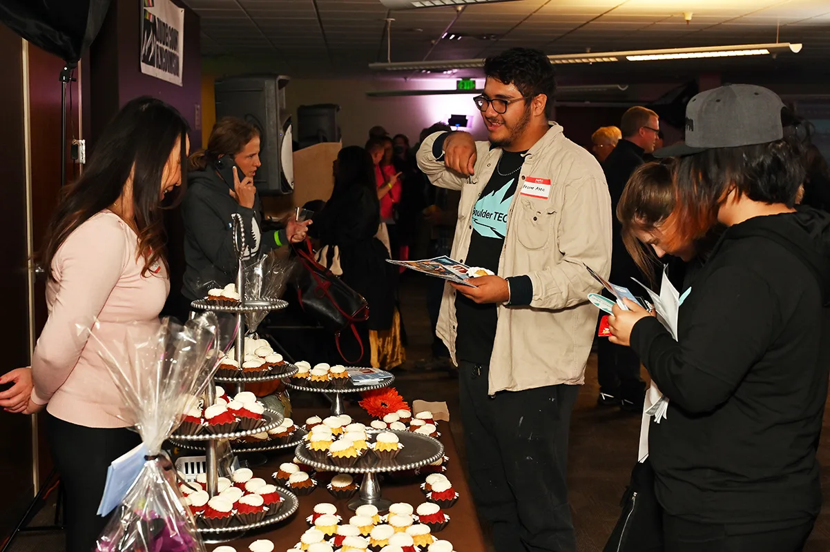 Attendees reading event programs beside a table of cupcakes at the Boulder County Film Commission fall event