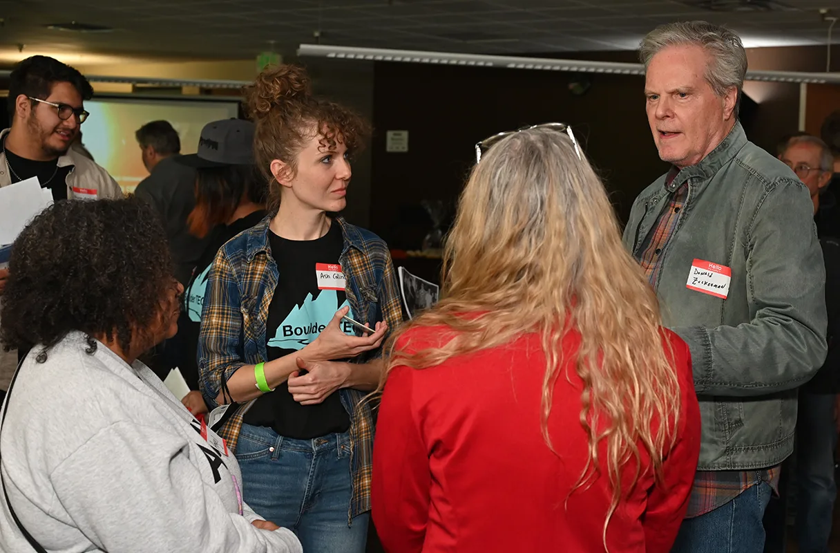 Attendees with name tags talking in a small group at the Boulder County Film Commission fall event