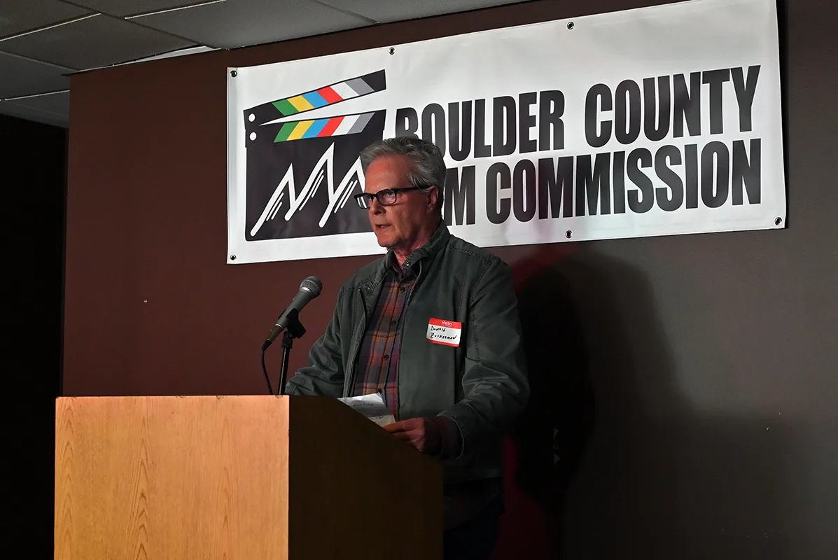 Speaker at a podium in front of the Boulder County Film Commission banner at the 2022 fall event