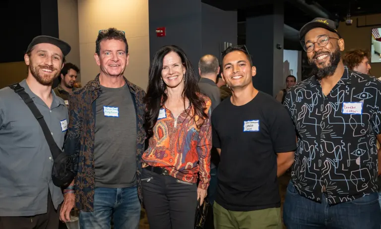 Five smiling attendees wearing name tags posing together at a Boulder County Film Commission Schmoozer