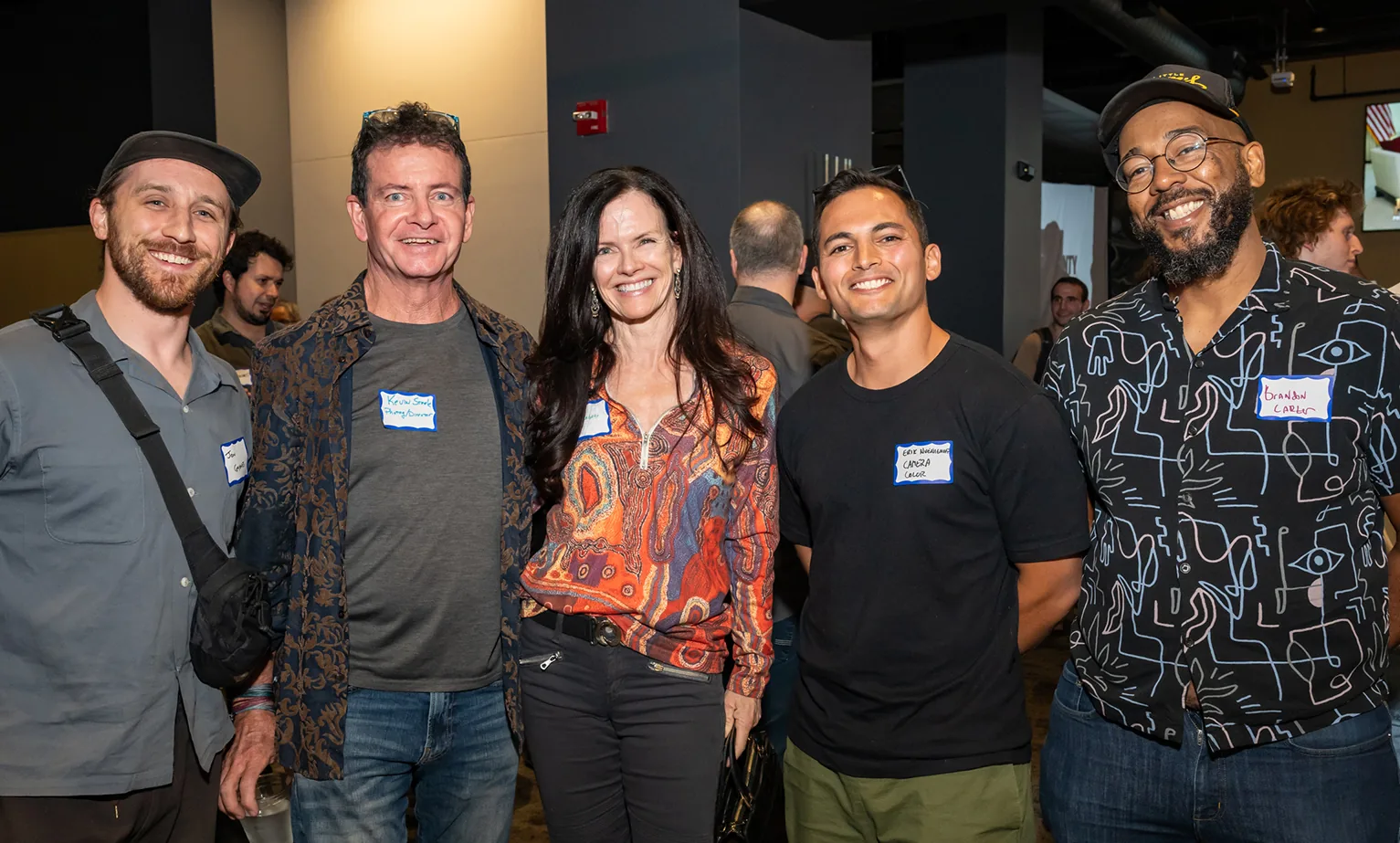 Five smiling attendees wearing name tags posing together at a Boulder County Film Commission Schmoozer