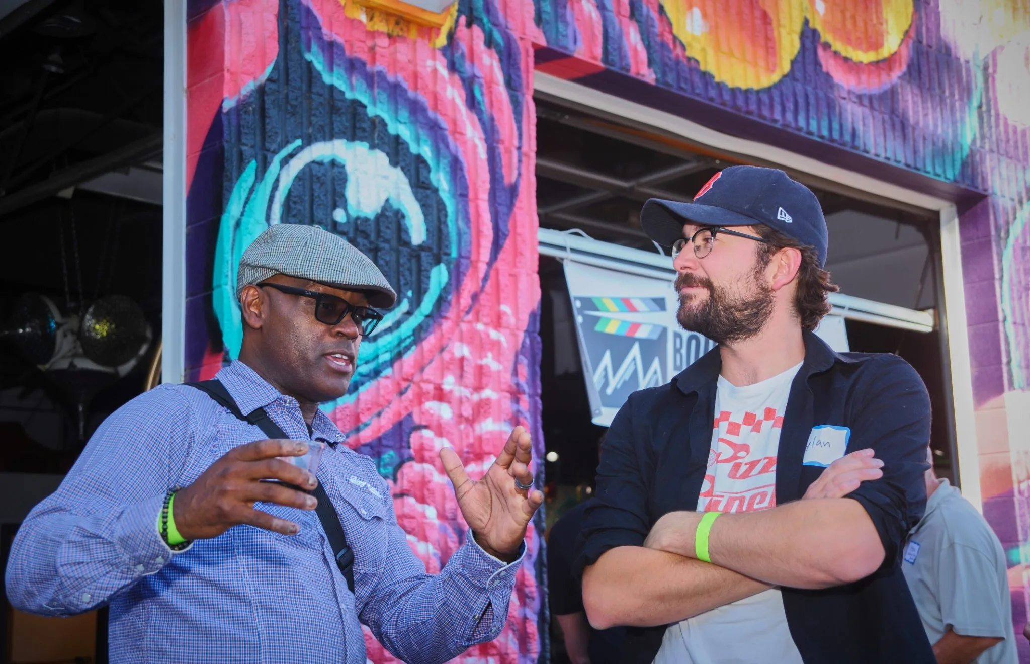 Two attendees talking in front of a colorful mural at the Boulder County Film Commission launch event