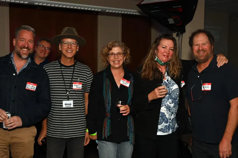 Six smiling attendees wearing name tags posing together at a Boulder County Film Commission Schmoozer
