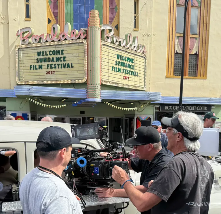 Film crew operating a cinema camera outside the Boulder Theater, whose marquee reads Welcome Sundance Film Festival 2027