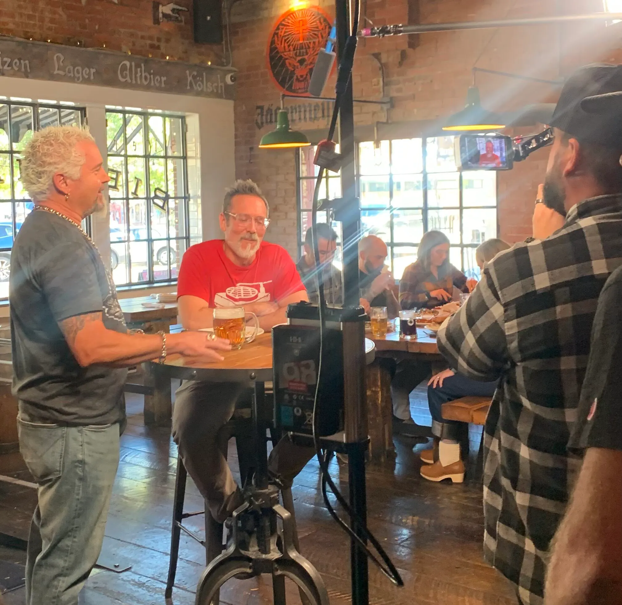 Camera crew filming two men talking at a table in a brewery