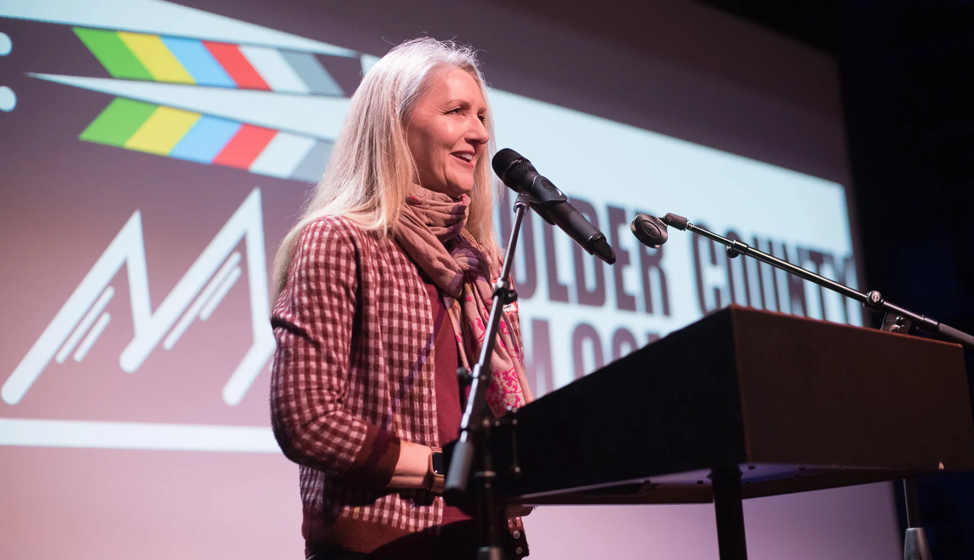 Speaker at a podium in front of a projected Boulder County Film Commission logo