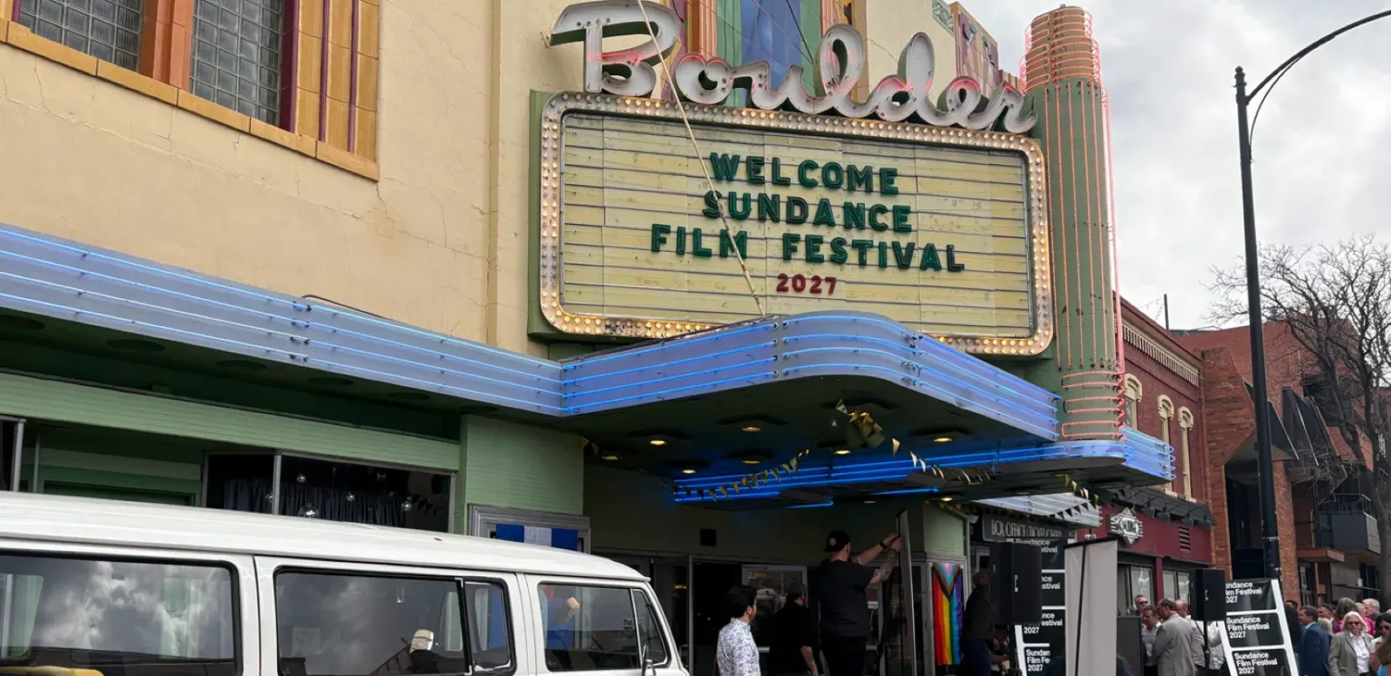 Boulder Theater marquee reading Welcome Sundance Film Festival 2027, with a VW bus parked out front and people gathered at the entrance