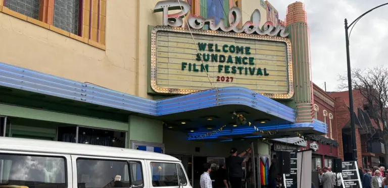 Boulder Theater marquee reading Welcome Sundance Film Festival 2027, with a VW bus parked out front and people gathered at the entrance