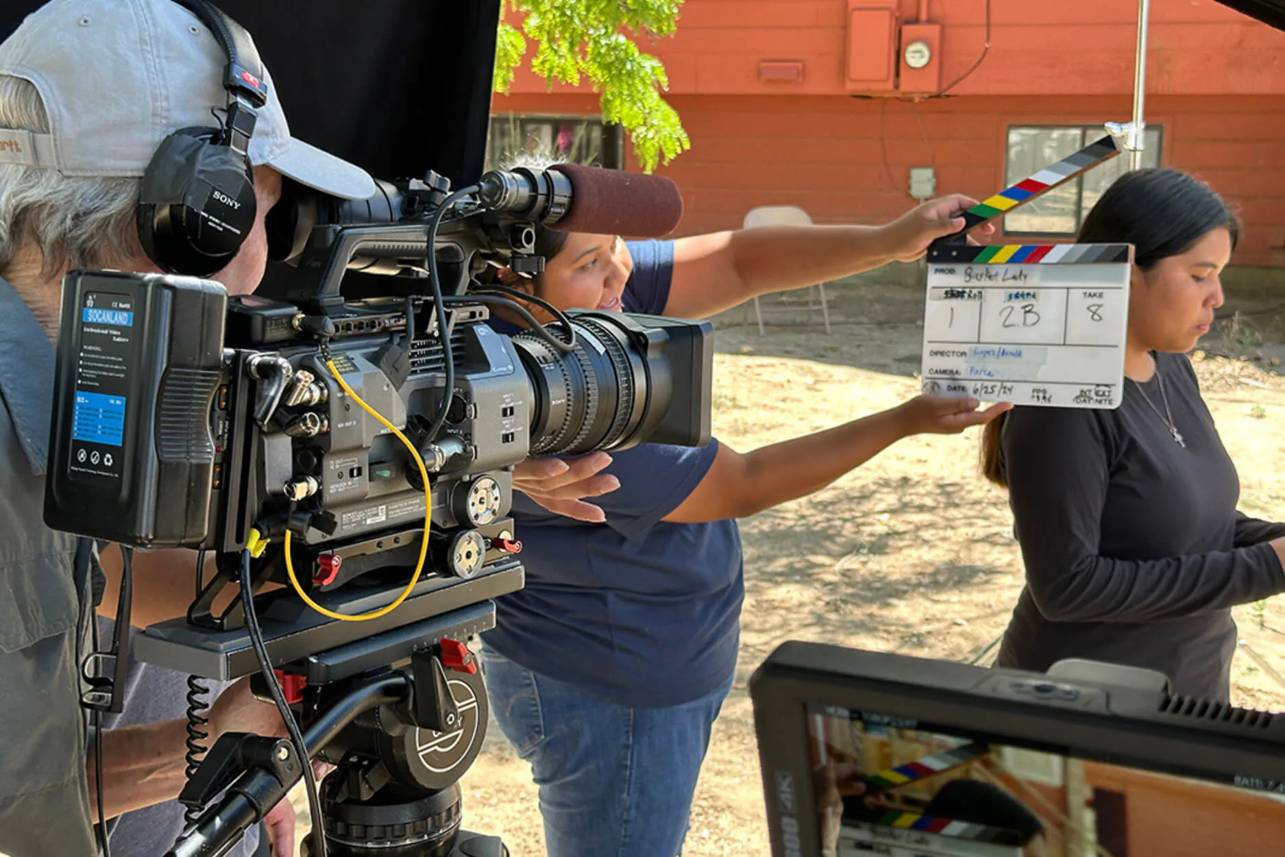 Camera operator filming outdoors as a crew member holds up a clapperboard