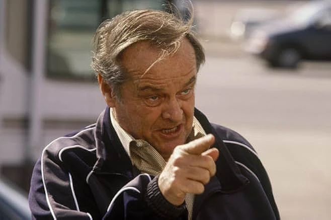 Close-up of Warren Schmidt, his hair windblown, pointing a finger toward the camera.