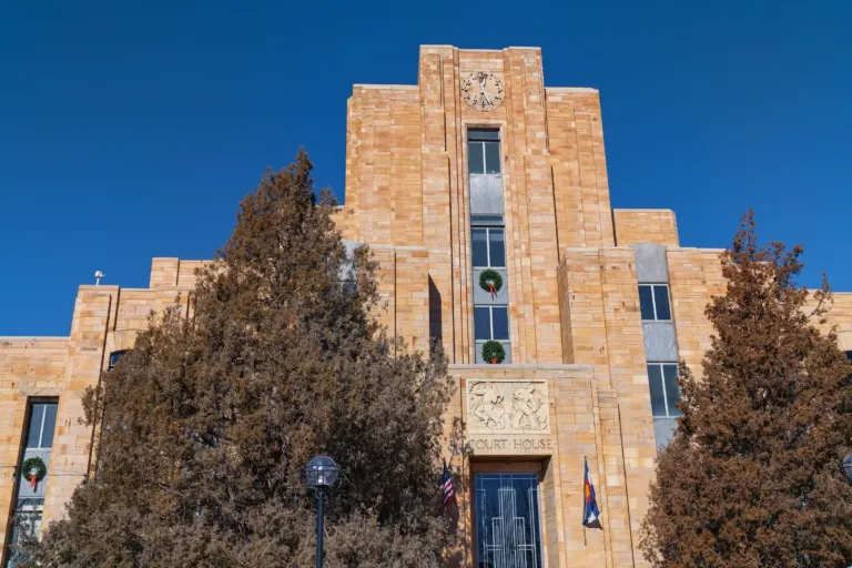 Looking up at a sandstone Art Deco tower with a clock, a carved relief panel and the words COURT HOUSE above the entrance.