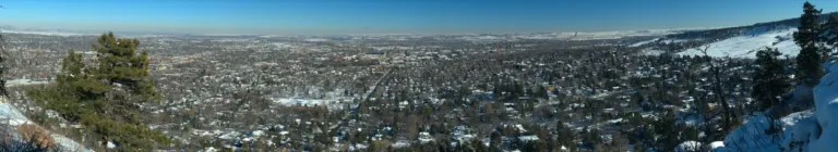 Snow-covered Boulder seen from Flagstaff Mountain, with the university campus at center and the plains reaching a hazy horizon