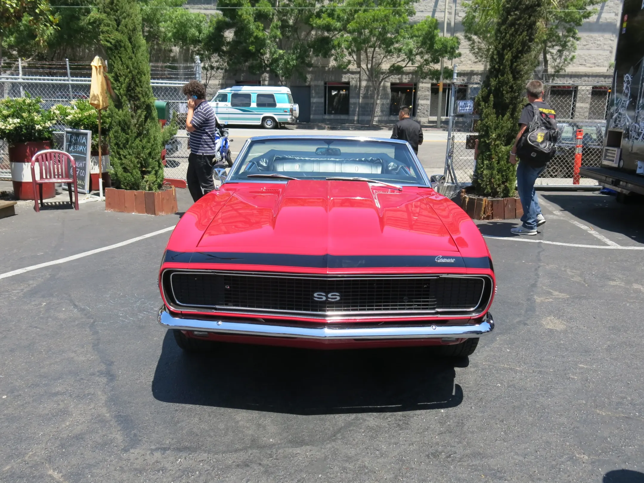 Red Camaro SS convertible with a black stripe and the top down, parked head-on in a food truck park lot