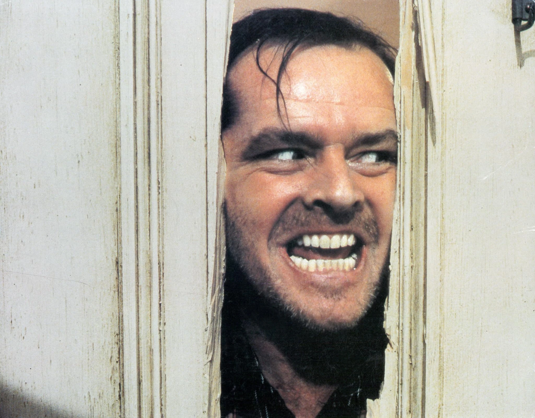 Jack Torrance grins wildly through the splintered gap he has chopped in a white bathroom door