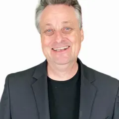 Portrait of filmmaker Tom Parkin in a dark blazer against a white background